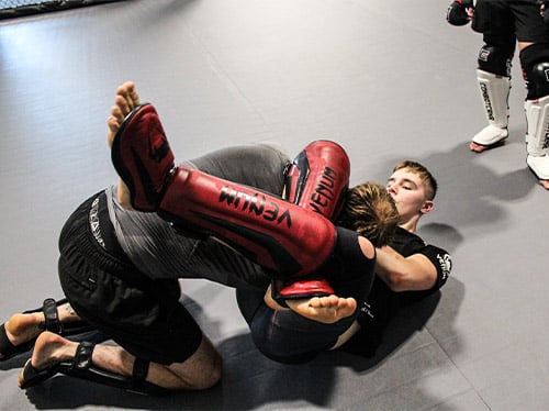 A group of young students are stretching on the ground in preparation for martial arts.