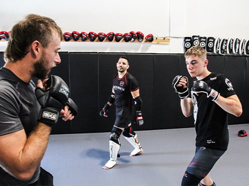 Two mma fighters are seen preparing to fight with Marco in the background.