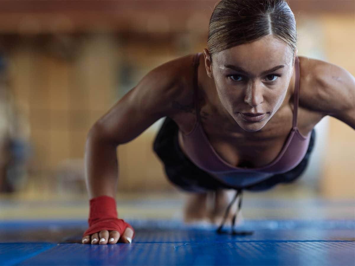 A muscular woman stares at the camera while planking for fitness.