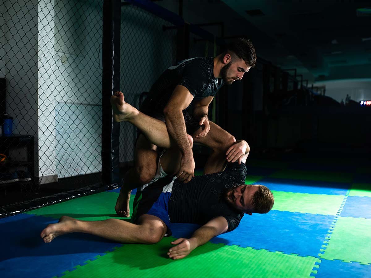 Two fit men engage in brazilian jiu jitsu and grapple each other on bjj mats.