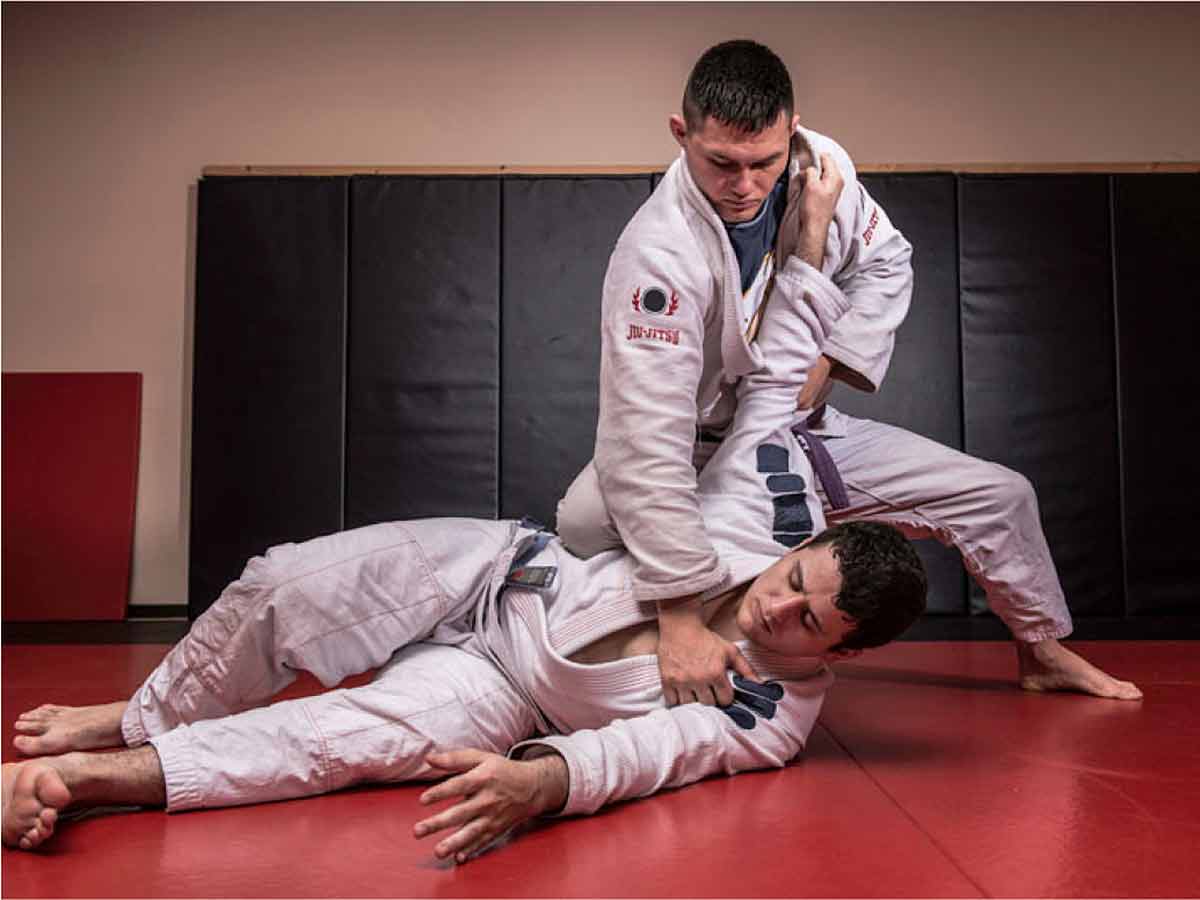 A man holds down his male martial arts partner.