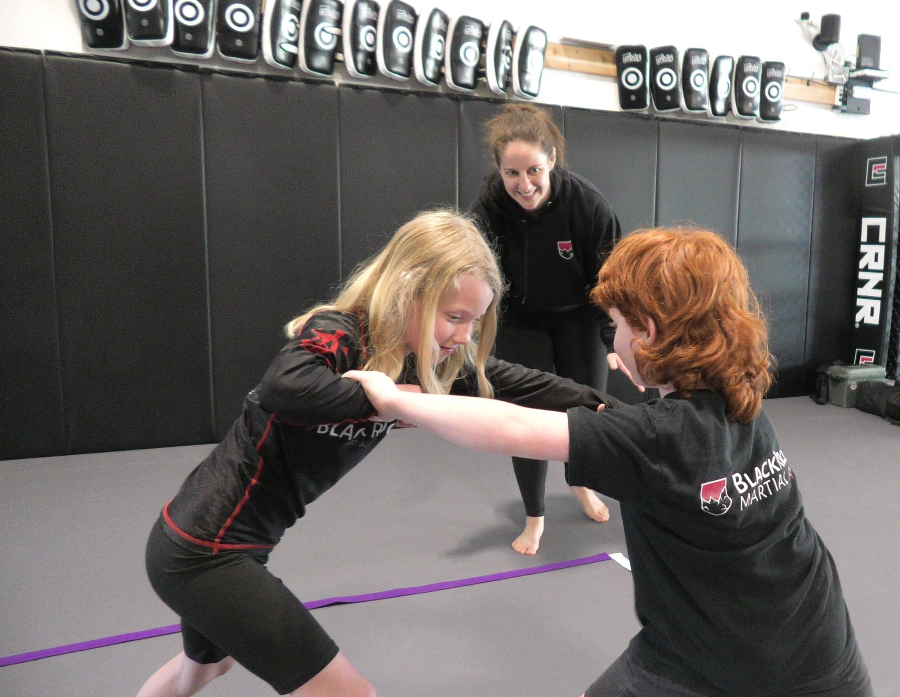 A group of young students are stretching on the ground in preparation for martial arts.